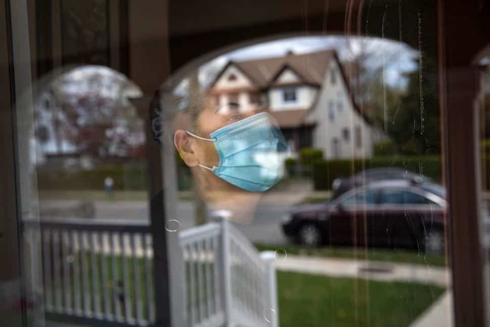 a man wearing a face mask looking out a window.