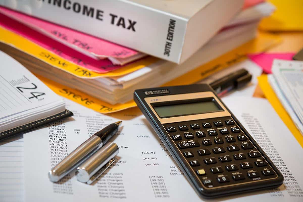 A calculator on a pile of books related to taxes.