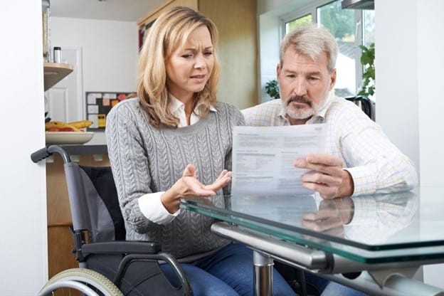 A man and woman in a wheelchair looking at a document.