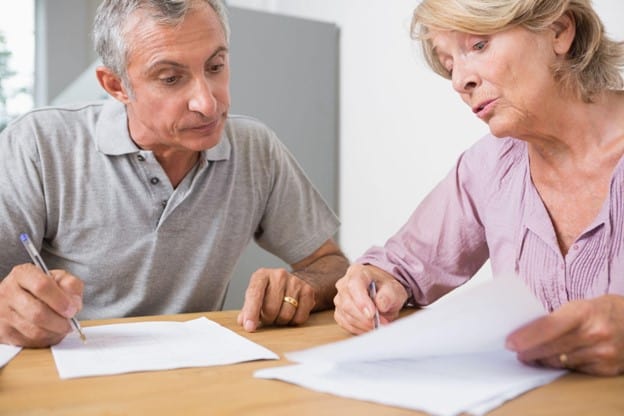 A man and woman are sitting at a table looking at papers.